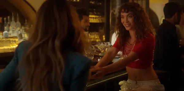 Feet wearing gold sandals with decorative yellow and pink floral designs