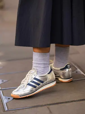 A guest wears silver Adidas sneakers outside