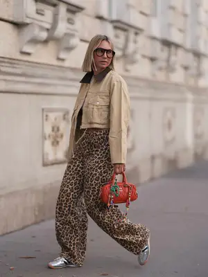 Karin Teigl seen wearing Andy Wolf black sunglasses, By Aylin Koenig white cotton basic cropped shirt, Bershka brown animal printed oversized long pants, Zara beige cropped cord jacket, Miu Miu orange leather Arcadie bag with colorful bag charms and Adidas silver leather 