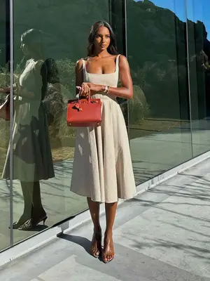 Jasmine Tookes wears a white sundress, red Hermes bag, and sandals