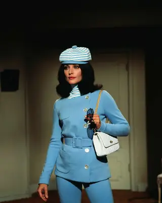 Sharon Tate wearing a blue suit with a striped pageboy hat and a white quilted purse
