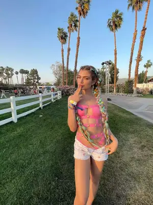 Valentina Sampaio wears a pink cutout bodysuit, unbuttoned jean shorts, and colorful braids