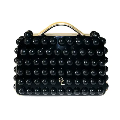 black acrylic bubble clutch with gold handle against plain background