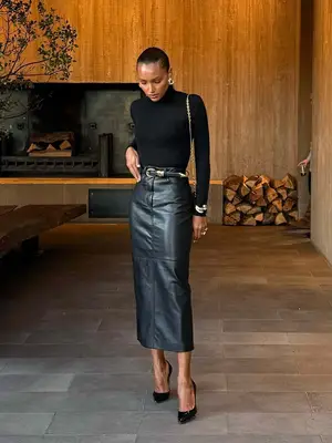 Jasmine Tookes wearing monochromatic all black outfit of turtleneck, leather skirt, heels, belt