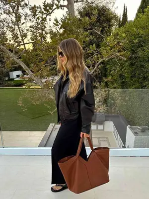 Sofia Richie Grainge wearing a black turtleneck, skirt, leather jacket, and carrying a tote