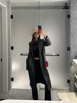Tatiana Elizabeth wearing a black top, black bootcut pants, black leather jacket and a red handbag