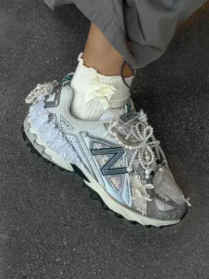 New Balance sneakers customized with lace details and pearls, person also wearing white ankle socks with bows