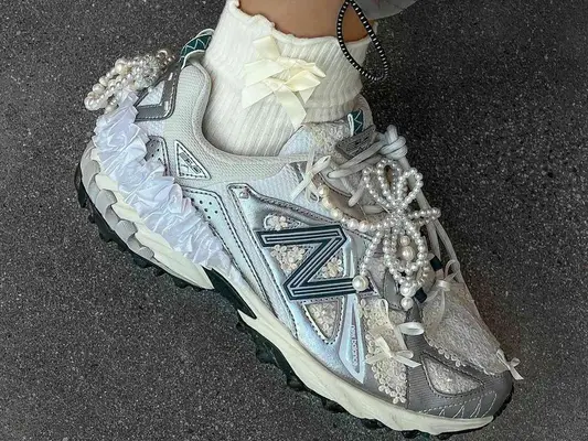 White and gray sneakers accessorized with pearls, ruffles, lace, and ribbons, styled with ankle socks with bows