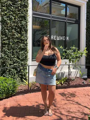 Julia Berit wearing a black crop tank, denim mini skirt, and flip flops 