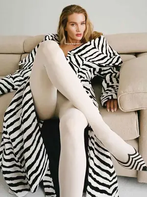 Rosie Huntington-Whiteley wears a zebra pring coat, white tights, black and white striped shoes, and pearls
