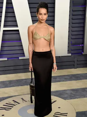 Zoe Kravitz wears a gold knit top and black low-rise slip skirt to the 2019 Vanity Fair Oscars afterparty