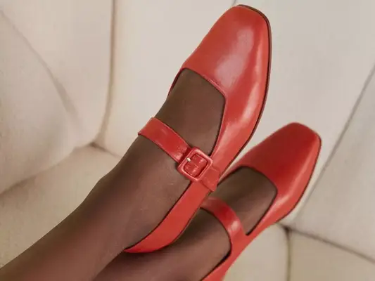 Crossed feet wearing red shoes in a Mary Jane flats style from Zou Xou