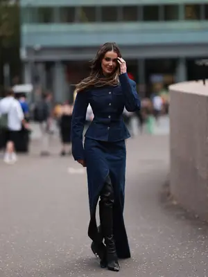 Woman wearing denim peplum top, maxi skirt with high slit, and knee-high boots