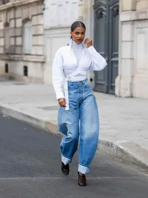 Woman wearing white collared wrap top, turtleneck, and horseshoe jeans with mesh heeled shoes