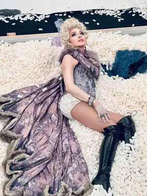 Madonna wears purple bodysuit with cape, white pantaloons, black lace-up knee-high boots, and Marie Antoinette wig