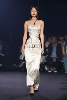 Model wears corseted white dress with buckled belt and black shoes at the Wiederhoeft Spring 2025 show