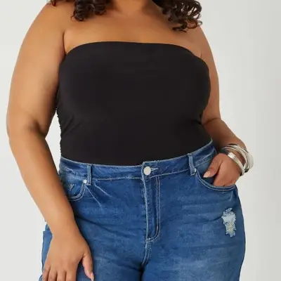 A model is wearing a black tube top tucked into jeans 
