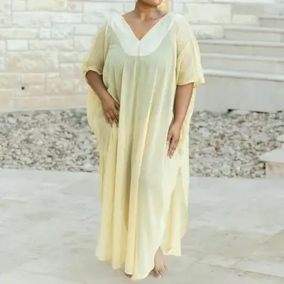Model is standing outside wearing a yellow kaftan 