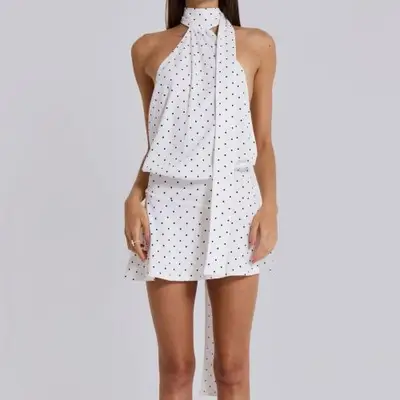 A model is wearing white backless mini dress with black dots.
