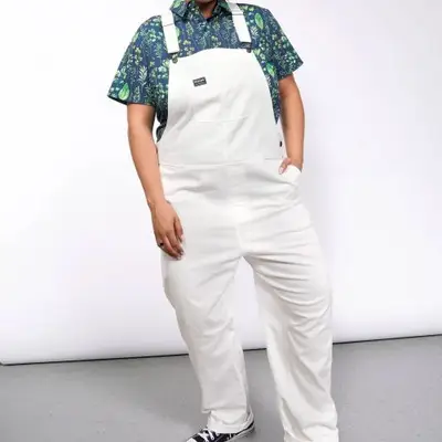 Model is wearing white denim overalls 