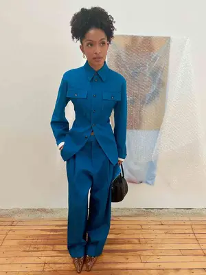 Yara Shahidi wears a tailored blue matching set, pointed-toe shoes, and carries a black handbag