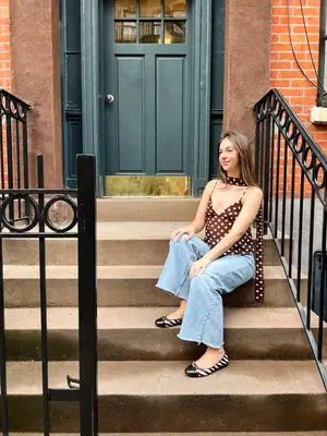 Person sitting on outdoor stairs wearing a polka dot top