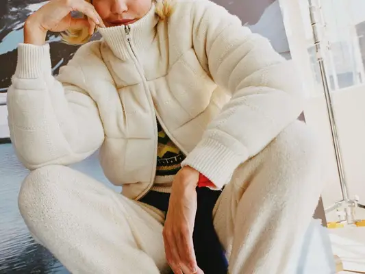 Close-up of Gigi Hadid wearing cashmere sweater, pants, and jacket from Guest in Residence