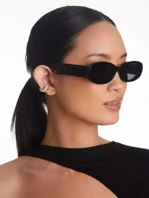 model wearing black oval-shaped sunglasses against plain background
