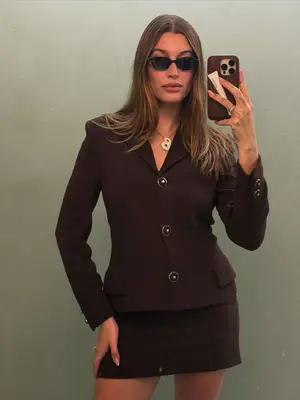 Hailey Bieber wears a chocolate brown skirt suit set and sunglasses