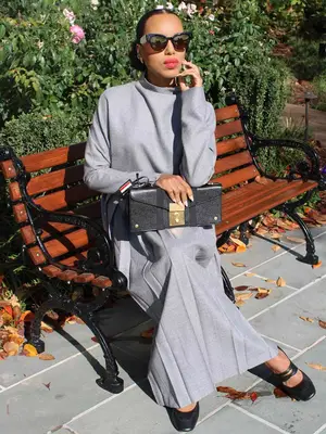 Kerry Washington wears a light gray set with black handbag, ballet flats, and sunglasses