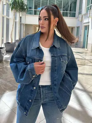 Ashley Graham wearing a blue denim jacket, jeans, and white tank