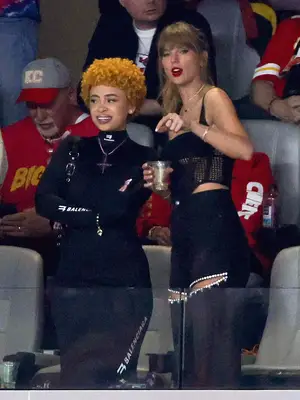 Taylor Swift and Ice Spice at football game both wearing black and silver outfits