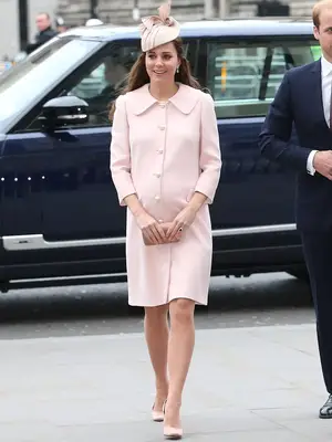 Kate Middleton wearing a light pink coat dress with a light pink fascinator, nude heels, and clutch