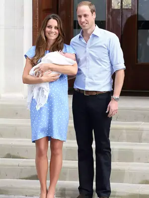Kate Middleton wears a blue and white polka-dot dress while posing for photos with Prince William and newborn Prince George