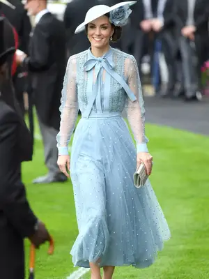 Kate Middleton wearing a light blue long sleeve dress and tilted hat with flower detail