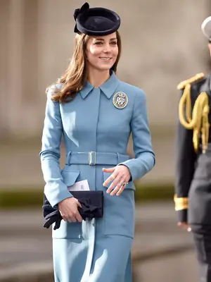 Kate Middleton wearing a light blue tailored dress coat with a navy fascinator