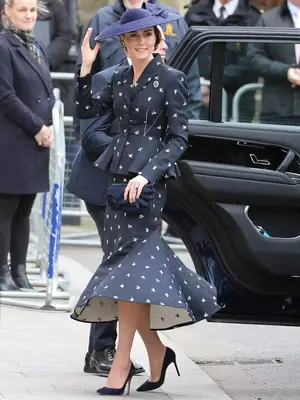 Kate Middleton wearing a navy printed skirt and top with a blue hat and heels