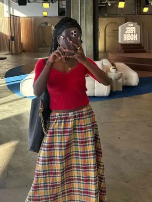 Toni Bravo taking a selfie while wearing a red top and tartan skirt