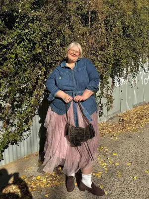 Abby Bible wearing a denim shirt, ruffled pink skirt, boho handbag, white socks, and loafers