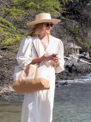 Connie Britton wearing a white dress and a large-brimmed straw hat on The White Lotus