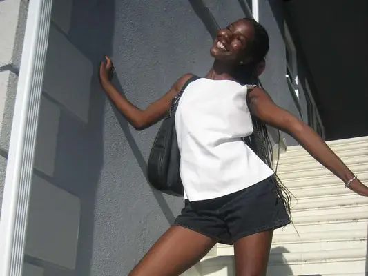 Woman wearing white top, black denim shorts, and black shoulder bag