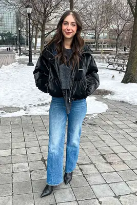 A person standing outside wearing a black coat and Mother Bookie Flood jeans