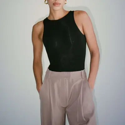 Close-up of model wearing black bodysuit and neutral trousers
