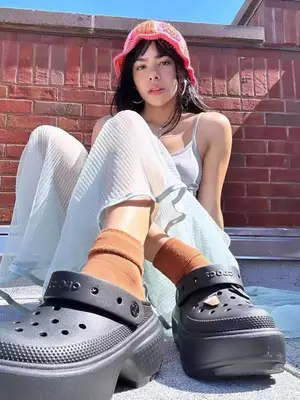 Antonia Gentry wearing a gray tank top, blue sheer mesh skirt, crocheted bucket hat, and black Crocs