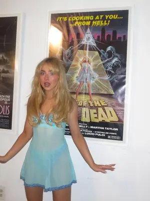 Sabrina Carpenter wearing a sheer blue dress in front of movie poster