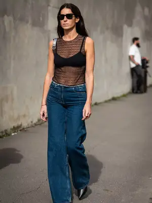 person walking with a mesh tank top, dark wash jeans, and sunglasses