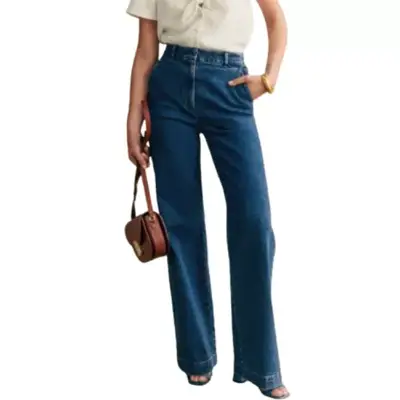 Sezane Matheo Trousers in dark blue denim on model styled with ivory button-down, block heels, and brown leather handbag