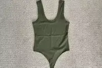 The Nuuds Seamless Scoop Tank Bodysuit on a white carpet