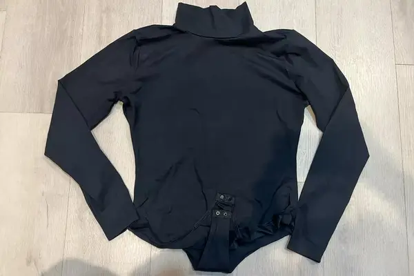 The Spanx Suit Yourself Long Sleeve Turtleneck Thong Bodysuit on a wood floor