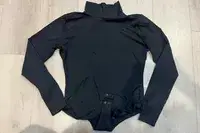 The Spanx Suit Yourself Long Sleeve Turtleneck Thong Bodysuit on a wood floor